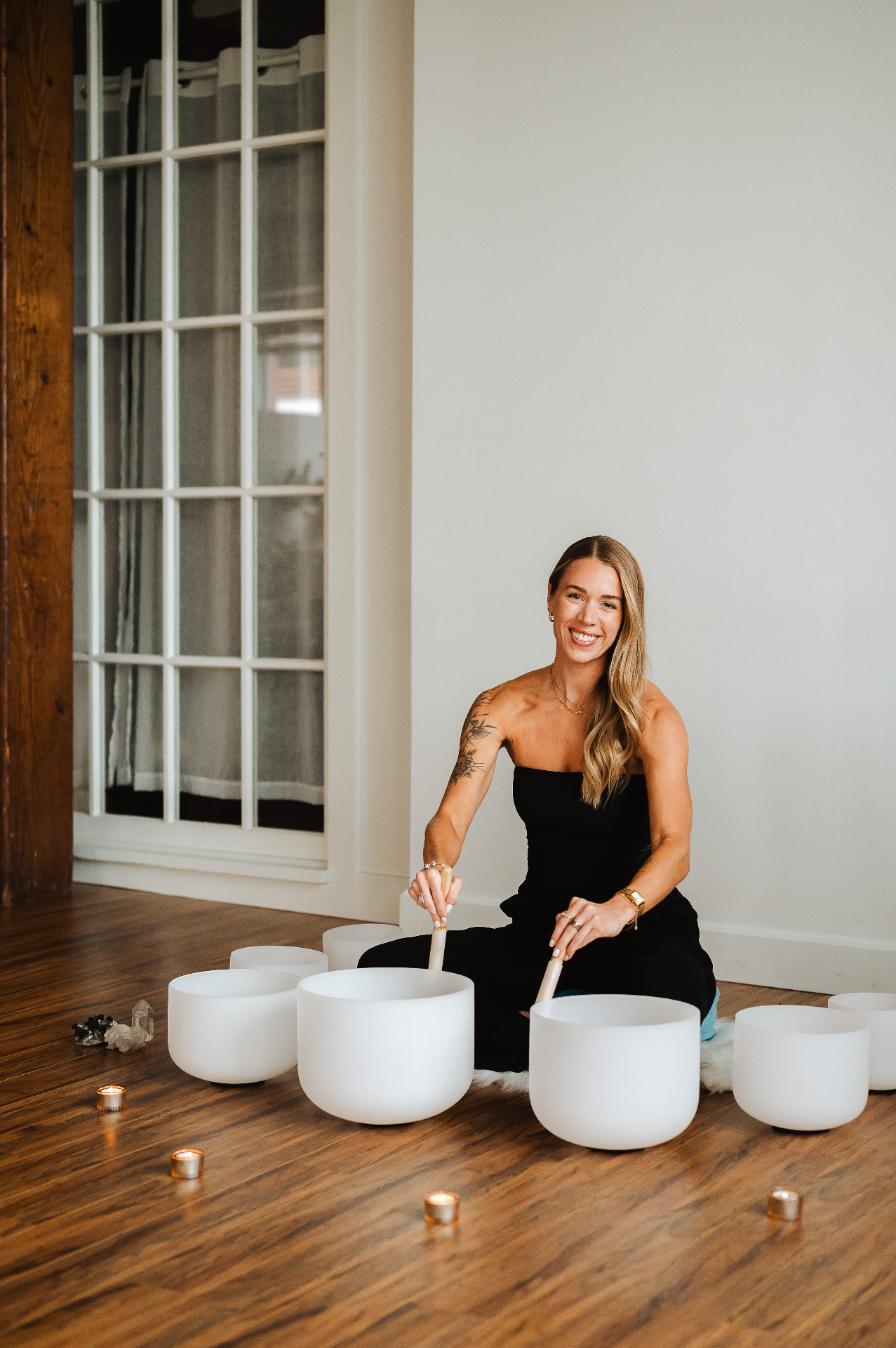 Kelli Blake smiling behind a circle of crystal singing bowls
