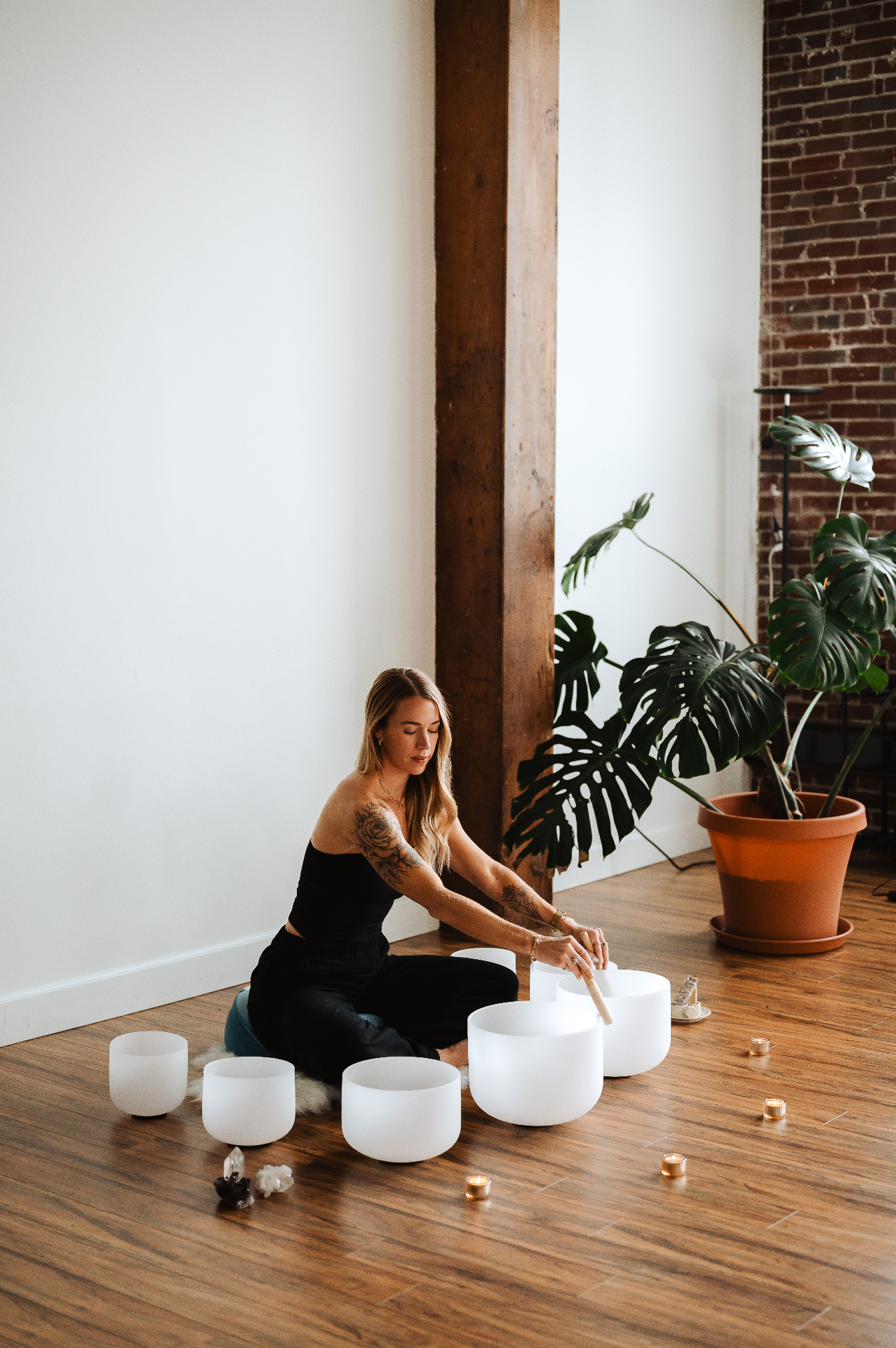Kelli Blake seated with crystal singing bowls in a loft studio