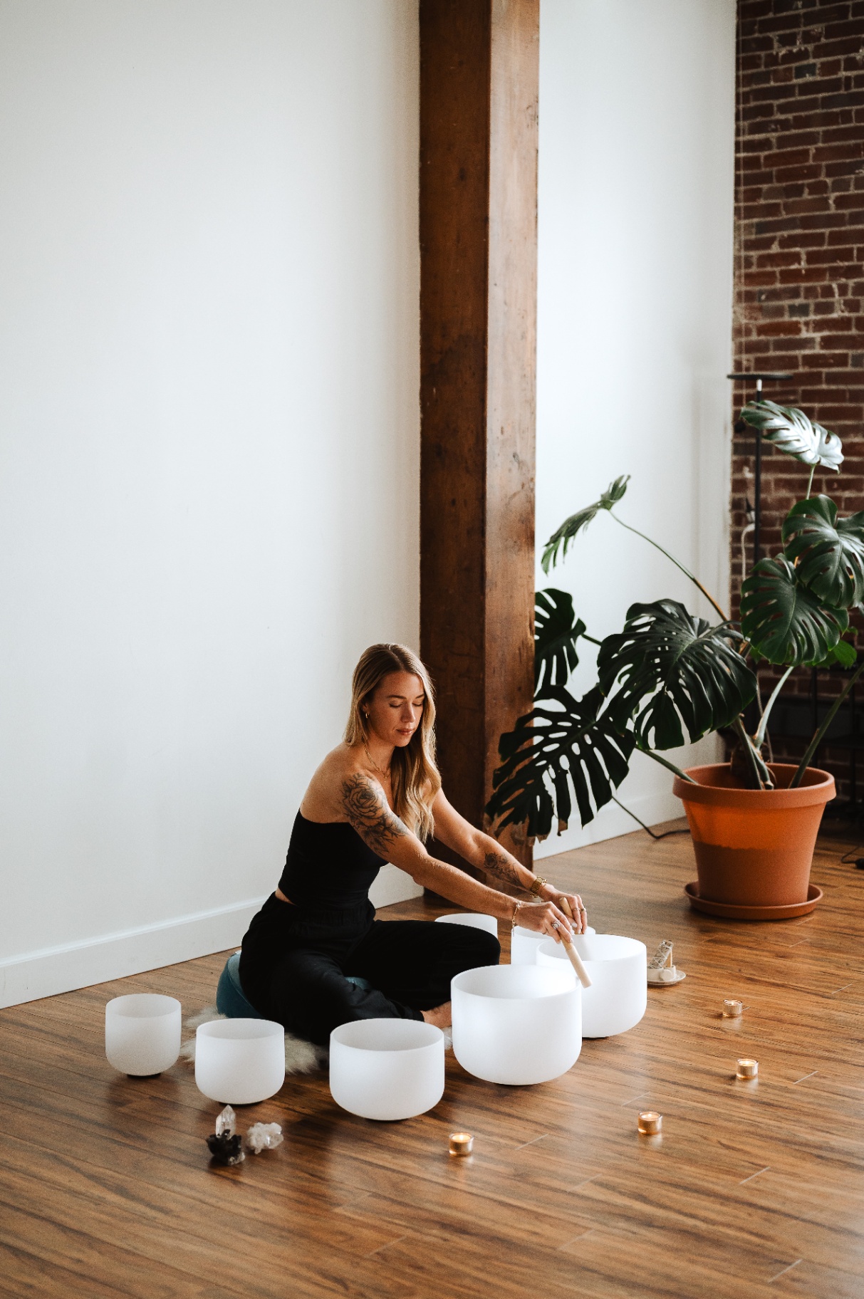 Kelli Blake playing crystal singing bowls on a wood floor